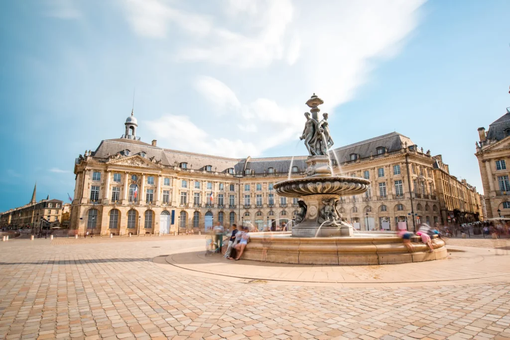 View on the famous La Bourse square with fountain in Bordeaux city, France. Long exposure image technic with motion blurred people and clouds