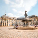 View on the famous La Bourse square with fountain in Bordeaux city, France. Long exposure image technic with motion blurred people and clouds